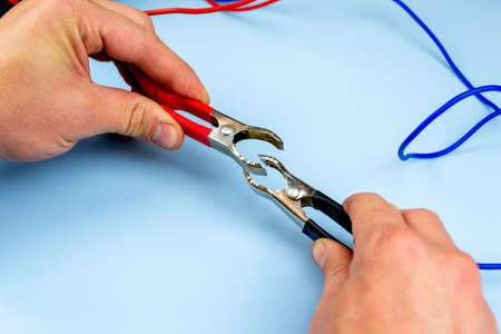 A man holds a jumper cable, on a blue background. close-upの写真素材