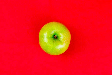 Green apple on a red background, close-upの写真素材