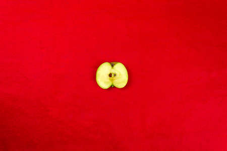 Apple cut in half on a red background, close up