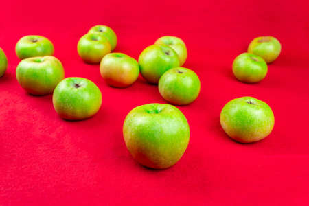 Green apples on a red background. Close-up