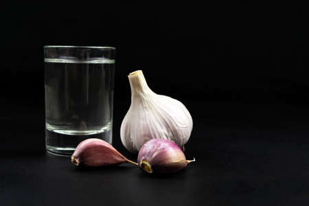 Glass of vodka and garlic on black backgroundの写真素材