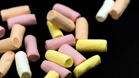 Multicolored little marshmallows on a black background