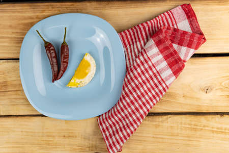 Top view of a cut fried egg on a blue plate with two peppers. Wooden table with red towel