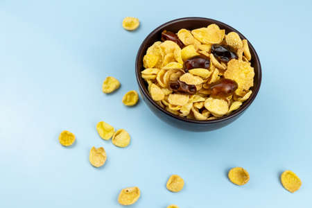 Healthy food corn flakes in plate close up with dates on blue background
