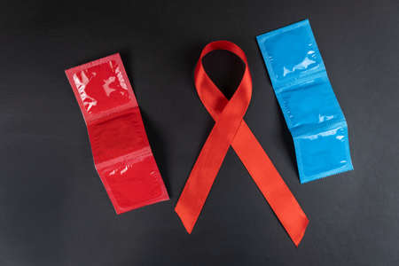 Multicolored condoms and red ribbon aids day on black backgroundの写真素材