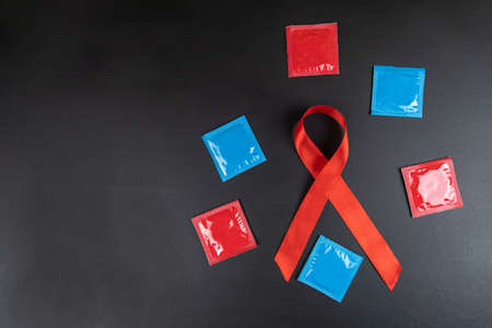 Multicolored condoms and red ribbon aids day on black backgroundの写真素材