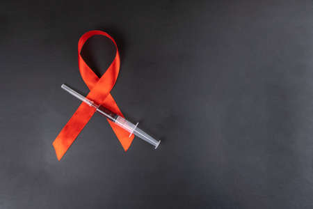 Medical concept, red AIDS Day ribbon and syringe with drugs on black backgroundの写真素材