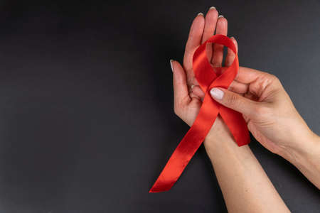 Female hands holding red ribbon HIV, AIDS awareness ribbon, healthcare and medicine concept. copy space.の写真素材