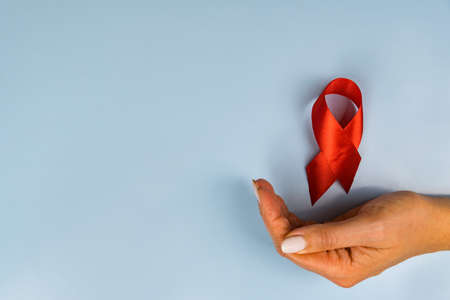 Woman's hand and in flight red ribbon aids day on blue backgroundの写真素材
