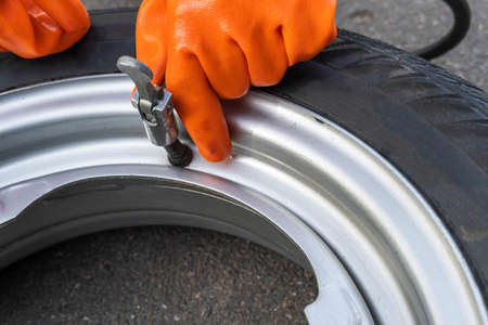 Woman hands hold the pump tip on the nipple of the wheel of the machine. Auto repairの写真素材