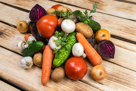 Assortment of fresh vegetables stacked by a slide on a wooden background. Close-up