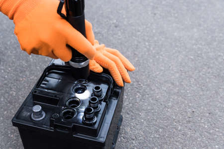 Mechanic shines a flashlight into the battery, diagnostics and repair of a car battery