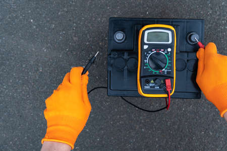 Mechanic checks the power of the battery, diagnostics and repair of the car batteryの写真素材