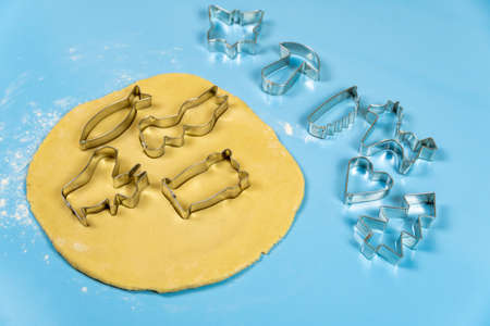 Cookie cutters on thinly rolled dough, on a blue background. Close-up