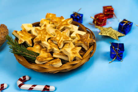 Christmas cookies in a wicker plate, next to colorful gifts on a blue background. Close-up