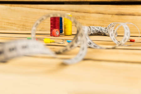 Multicolored skeins of sewing thread and a reel from a sewing machine with a pink thread on a wooden...