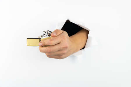 The girl's hand holds a gold lighter through a hole in the wall. Fire ignition device.
