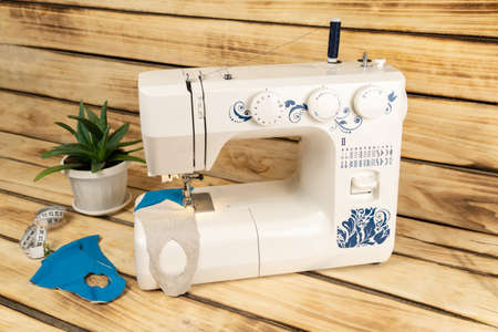 A white sewing machine on which medical masks for coronavirus are sewn. Sewing and health care...