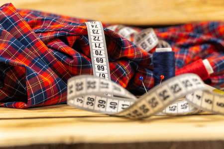 Measuring tape, tailor's pins, sewing thread on the background of a plaid shirt. Women's work and hobbies.の写真素材