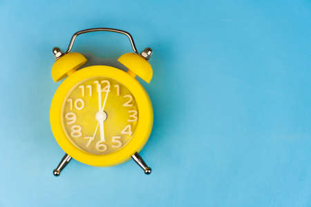 Yellow alarm clock close-up on a blue background. It's Blue Monday time. Copy space