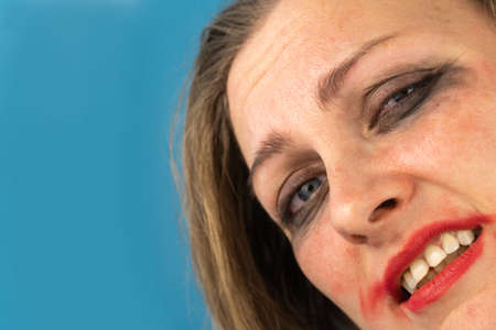 Sad woman with rubbed makeup, pain on her face. Blue background. Free space for text