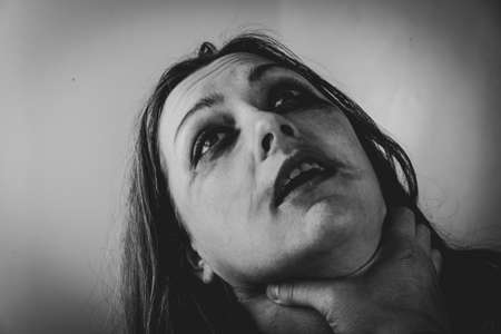 Scared eyes of a woman at the moment of suffocation. A man's hand grips a woman's neck. Male violence conceptの写真素材