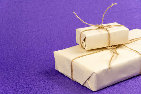 Gifts wrapped in white paper and tied with burlap rope, and colorful ribbons on a purple background. Free space for entering textの写真素材