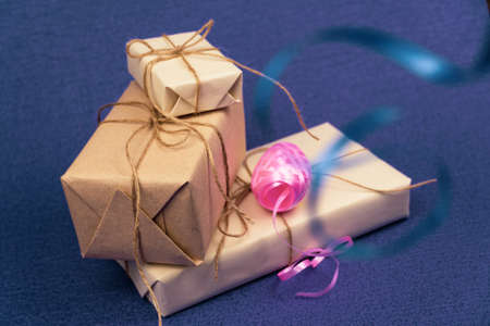 Gifts wrapped in white paper and tied with burlap rope, and colorful ribbons on a purple background. Free space for entering textの写真素材