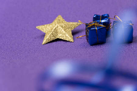 Christmas toy in the form of a star and small gifts on a violet background. Christmas backgroundの写真素材
