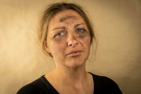 Sad face of a lonely homeless woman on a brown background. Lack of money and home