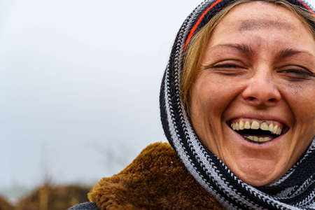 Close-up of a dirty woman's face. A dirty bum smiles and shows black teeth on the background of a landfill. Free space for textの写真素材