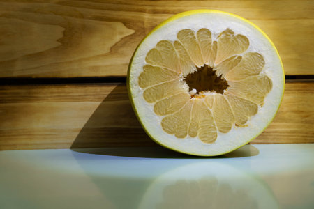 Half of the cut pomelo fruit against the background of boards in the lighting of a lantern. Free space for textの写真素材