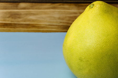 Close-up of a yellow pomelo on a blue background. Free space for entering text. Pomelo fruits on a blue background.の写真素材