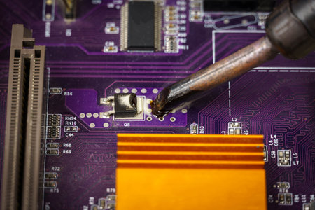 View of the soldering iron tip and the purple computer motherboard. Soldering iron solder the microcircuitの写真素材