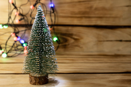 Artificial Christmas tree and garland on a wooden background, shallow depth of field. Christmas background with copy spaceの写真素材