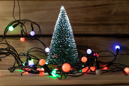 Artificial Christmas tree and garland on a wooden background, shallow depth of field. Christmas...