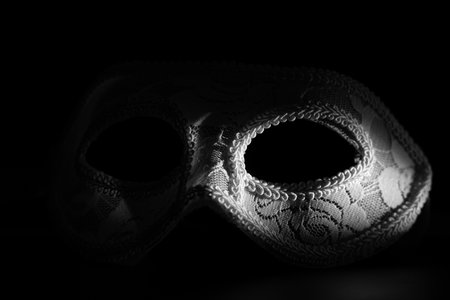 White festive carnival mask in the shadow of a point light on a black background. Mystery and mysticism conceptの写真素材