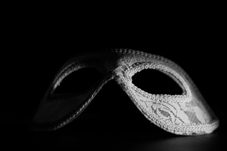 White festive carnival mask in the shadow of a point light on a black background. Mystery and mysticism conceptの写真素材