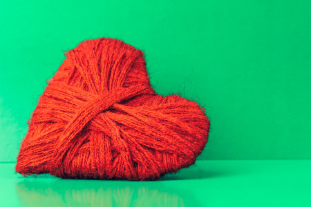 Heart on a green background, with copy space. Homemade heart made of thread. The concept of romance, love. Valentine's dayの写真素材