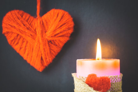 Valentine's Day. Red burning candle and homemade hearts on a black background The concept of dating, romance, love. shallow depth of fieldの写真素材