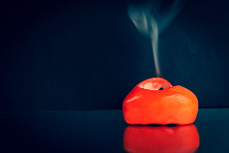 Extinguished red heart shaped candle with smoke from the wick on a black background. Nice frame for an article about love and Valentine's Day.の写真素材