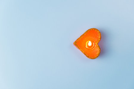 Top view of a burning candle in the form of a heart on a blue background. copy space. Valentine's dayの写真素材