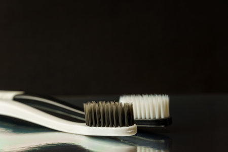 Close-up of black and white toothbrushes on a black background. Oral hygiene conceptの写真素材