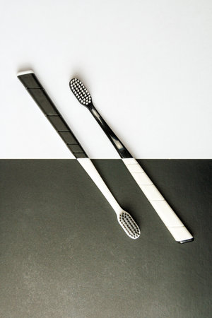 Two black and white toothbrushes on a monochrome background. The concept of balance and harmony of...