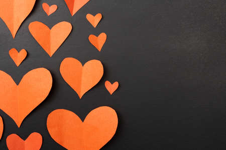 Hearts on a black background with copy space. Red paper hearts. Valentine's Day.