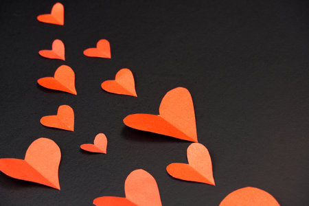 hearts on a black background with copy space. Red paper hearts. Valentine's Day card.