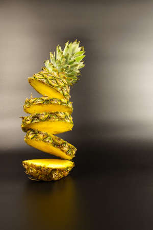 Flying ripe pineapple, cut into slices, on a black background. Pineapple frozen in flight
