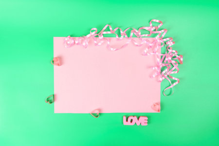 Pink copied space on a green background, next to hearts, serpentine and the inscription LOVE on a green background. Postcard until Valentine's Day.の写真素材