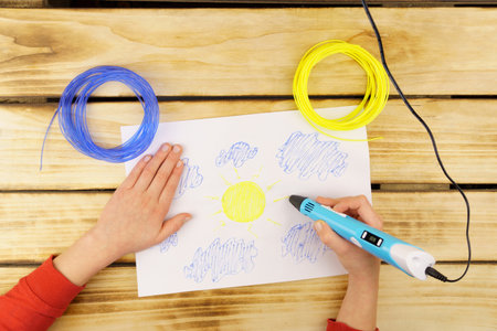 Using a 3D pen, I create a child's hands a 3D model of the sky, blue clouds and a yellow sky....