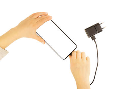 Children's pens insert the plug of the charger into a mobile phone, isolated on a white background. Smartphone in the middle is isolatedの写真素材